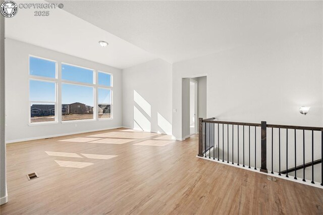 unfurnished living room featuring light wood-style floors, visible vents, baseboards, and an inviting chandelier