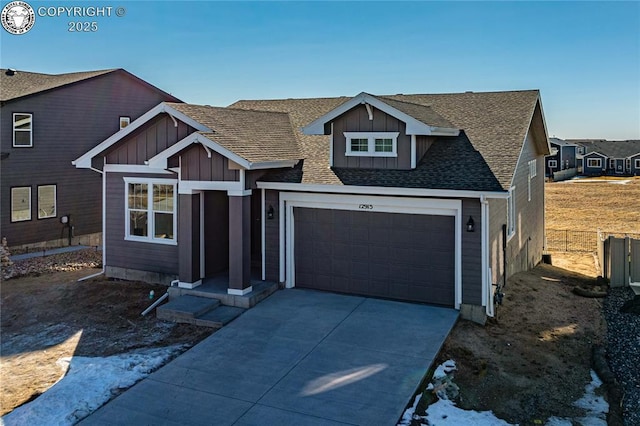 view of front of property featuring roof with shingles, concrete driveway, board and batten siding, fence, and a garage