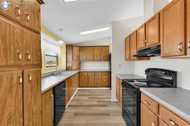 kitchen featuring light countertops, brown cabinetry, a sink, under cabinet range hood, and black appliances