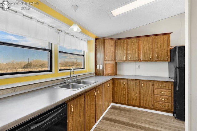 kitchen featuring black appliances, brown cabinets, a sink, and decorative light fixtures