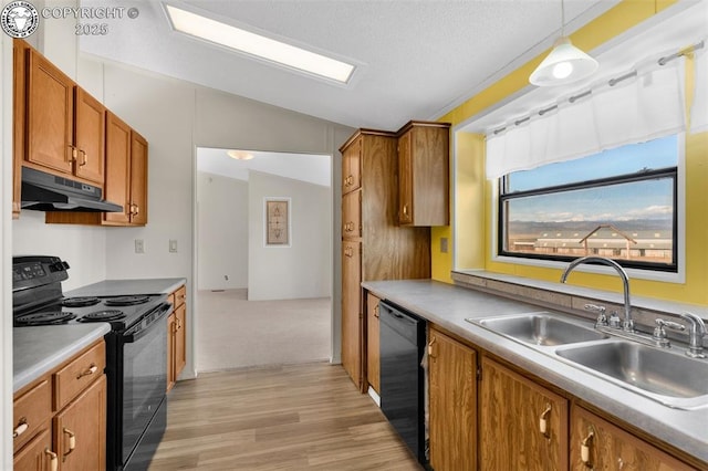 kitchen featuring under cabinet range hood, a sink, light countertops, black appliances, and pendant lighting