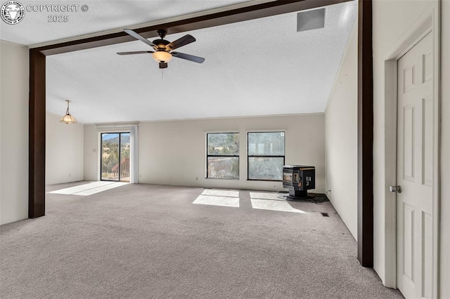 unfurnished living room featuring light colored carpet, ceiling fan, a wood stove, vaulted ceiling with beams, and a textured ceiling