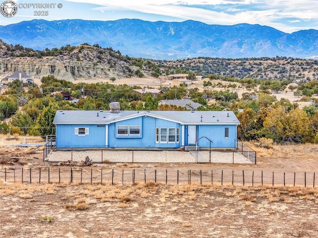 view of front of house with fence private yard, a mountain view, and a rural view