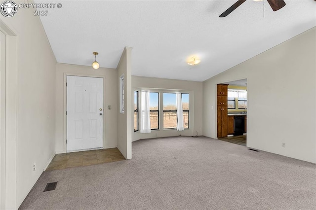 entrance foyer with light colored carpet, vaulted ceiling, visible vents, and ceiling fan