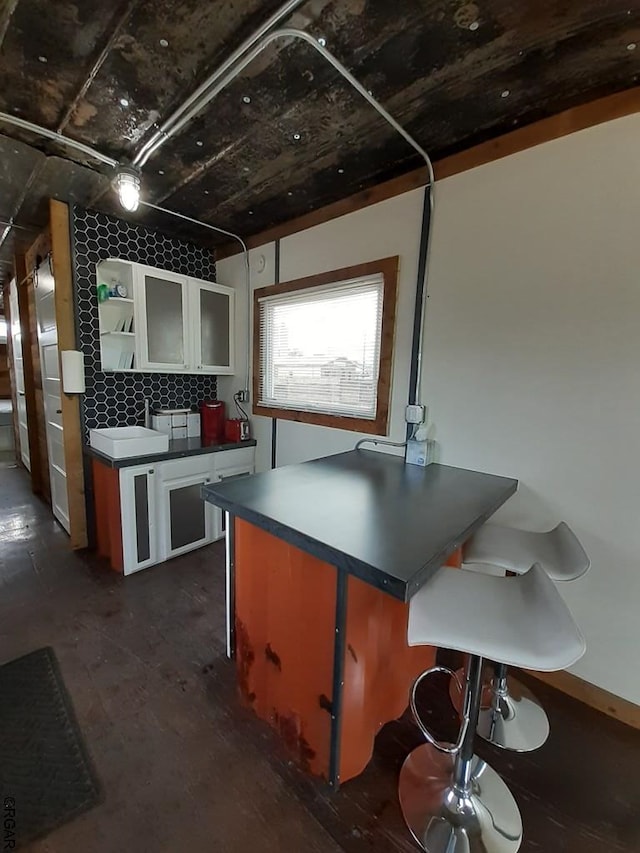 kitchen featuring white cabinetry, a kitchen breakfast bar, and sink