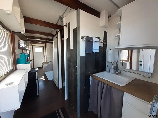 kitchen featuring sink, plenty of natural light, white cabinets, and beamed ceiling