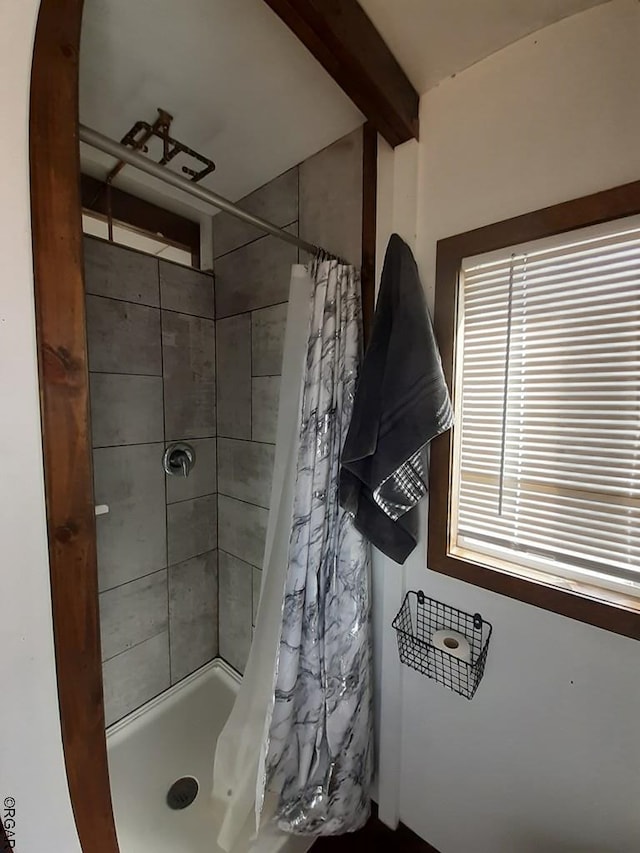 bathroom with walk in shower and beamed ceiling