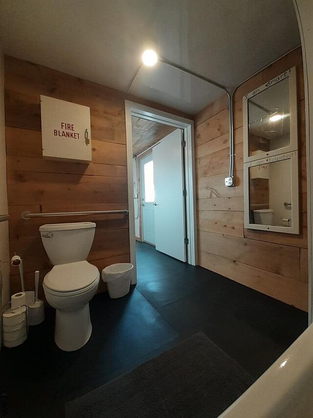 bathroom featuring toilet and wood walls