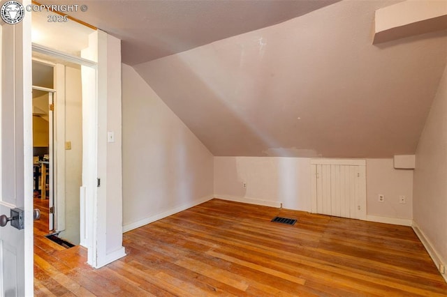 bonus room with lofted ceiling and light wood-type flooring