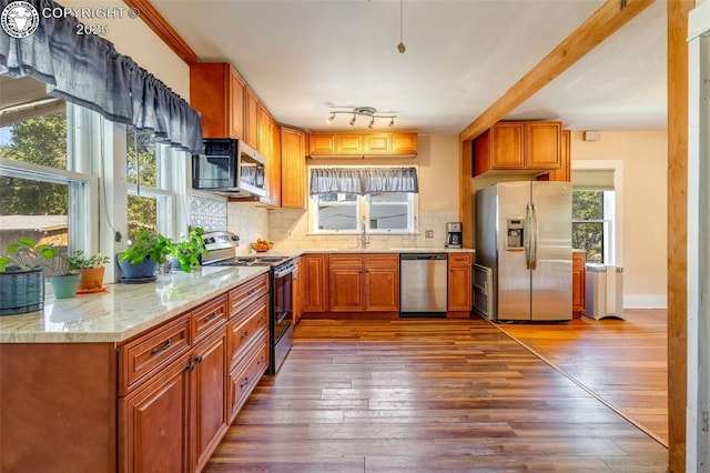 kitchen featuring sink, stainless steel appliances, light stone counters, dark hardwood / wood-style flooring, and decorative backsplash