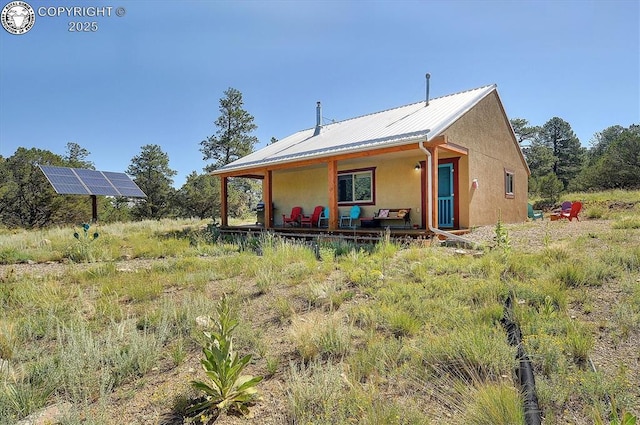 214 Durfee Cir, Westcliffe, CO 81252 - back of property featuring ground mounted solar panels, stucco siding, and metal roof