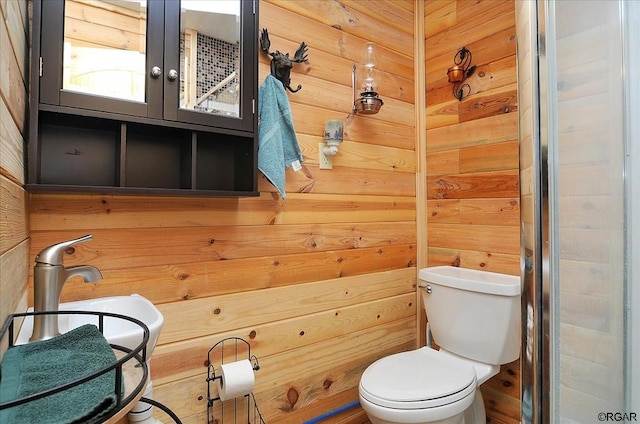 bathroom featuring wooden walls and toilet