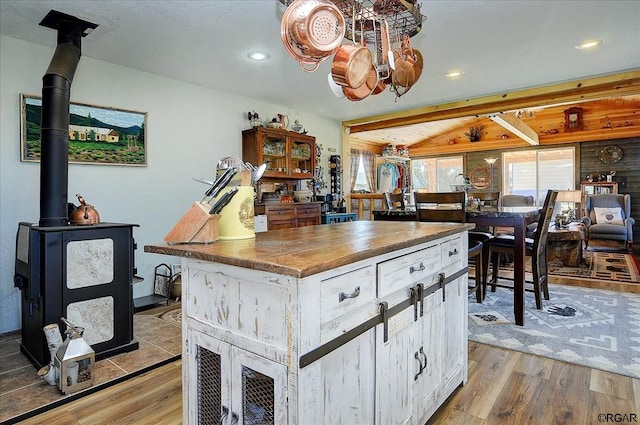 kitchen featuring a center island, a wood stove, wood counters, and light hardwood / wood-style floors