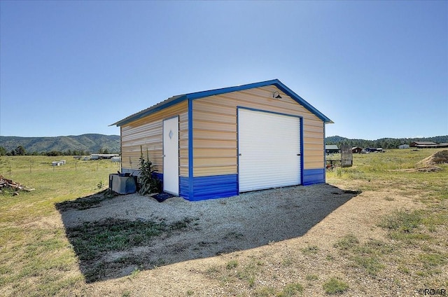 view of outbuilding with a rural view, a mountain view, and a garage