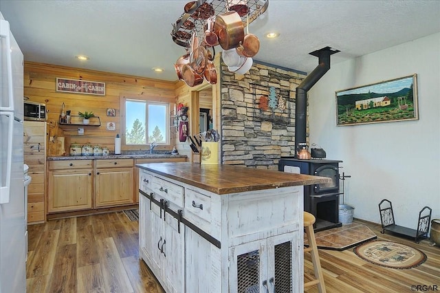 kitchen featuring a wood stove, wood counters, light hardwood / wood-style floors, light brown cabinetry, and wood walls