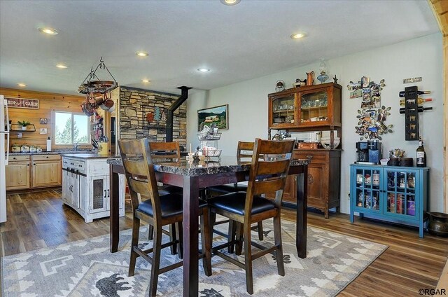 dining space featuring dark wood-type flooring, sink, and a wood stove