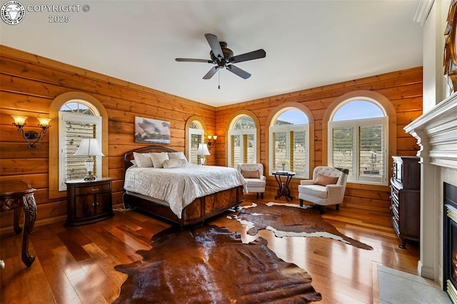 324 Elk View Ct, Canon City, CO 81212 - bedroom featuring wood walls, a fireplace with flush hearth, hardwood / wood-style flooring, and ceiling fan