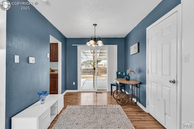 entryway featuring a textured ceiling, a chandelier, and light wood-type flooring