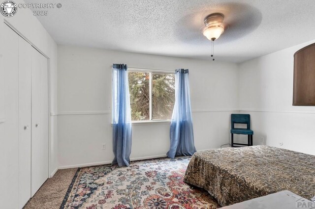 carpeted bedroom featuring a textured ceiling, a closet, and ceiling fan