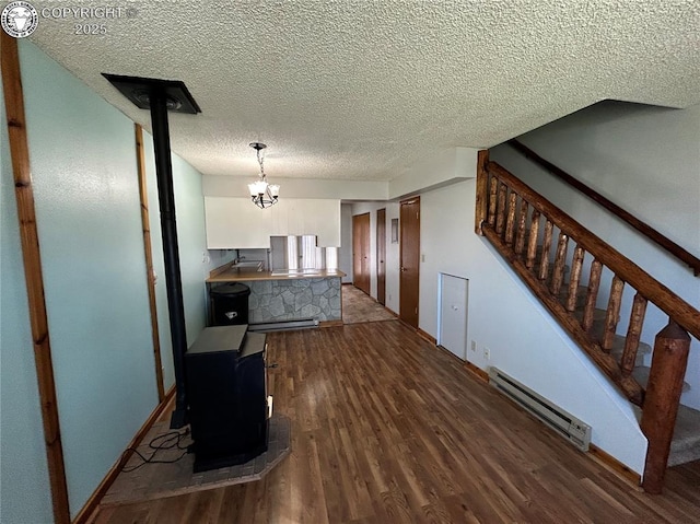 9 Granada Ct Unit 5, Westcliffe, CO 81252 - dining space featuring baseboard heating, a wood stove, wood finished floors, baseboards, and a textured ceiling