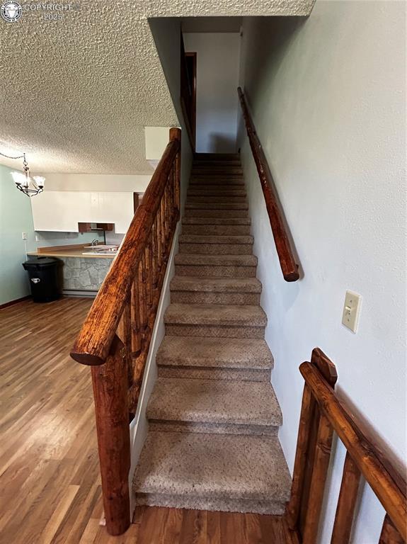9 Granada Ct Unit 5, Westcliffe, CO 81252 - stairway with wood finished floors, a chandelier, and a textured ceiling