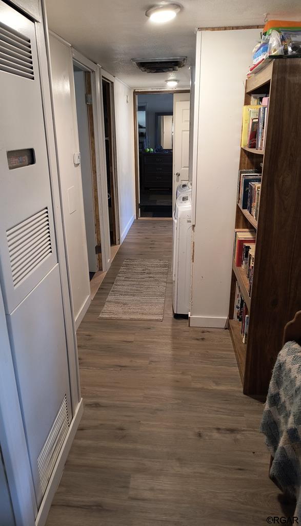 hallway with washer / clothes dryer and dark wood-type flooring