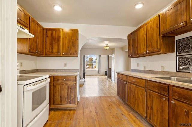 kitchen with sink, electric range, and light wood-type flooring