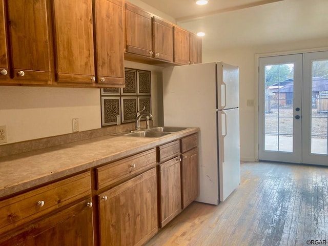 kitchen with sink, light hardwood / wood-style floors, french doors, and white refrigerator