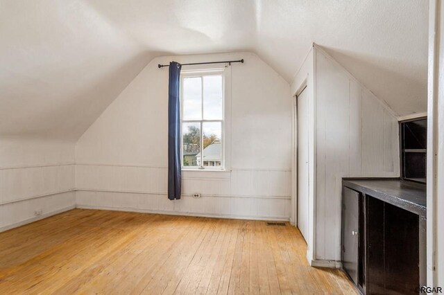 bonus room with lofted ceiling and light wood-type flooring