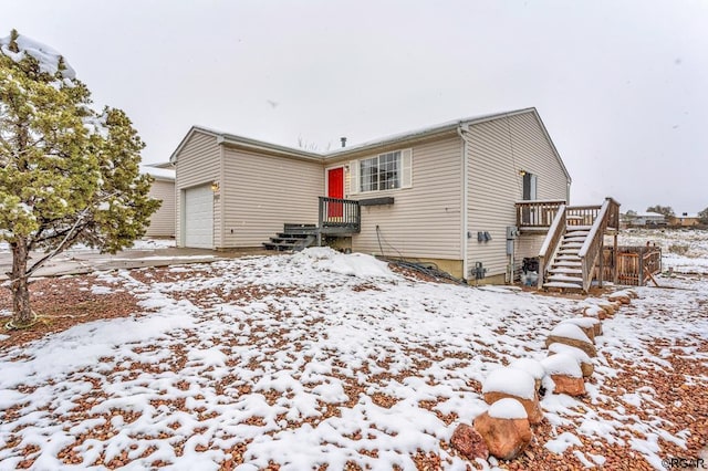 snow covered back of property featuring a garage