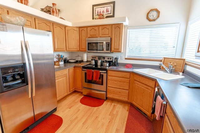 kitchen with a healthy amount of sunlight, appliances with stainless steel finishes, sink, and light hardwood / wood-style flooring