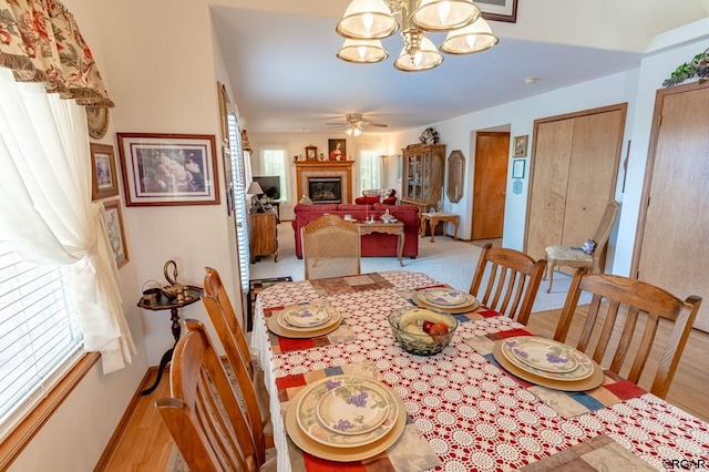 dining area with ceiling fan with notable chandelier and light wood-type flooring