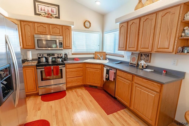 kitchen featuring vaulted ceiling, appliances with stainless steel finishes, sink, and light hardwood / wood-style floors