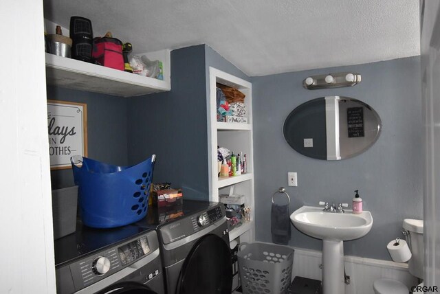 bathroom featuring washing machine and dryer, vaulted ceiling, sink, and a textured ceiling