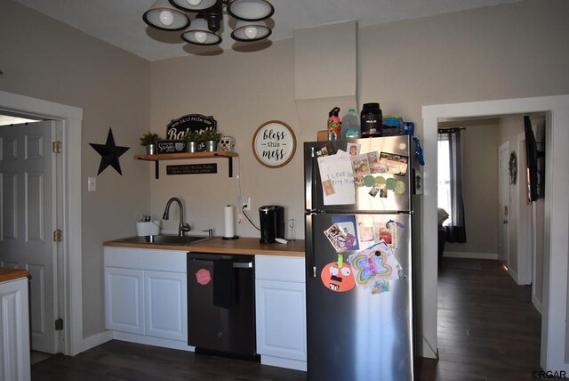 kitchen featuring butcher block countertops, stainless steel refrigerator, black dishwasher, sink, and white cabinets