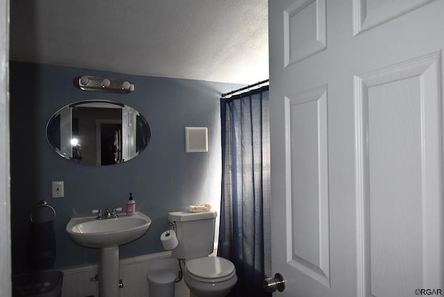 bathroom with a shower with curtain, sink, a textured ceiling, and toilet