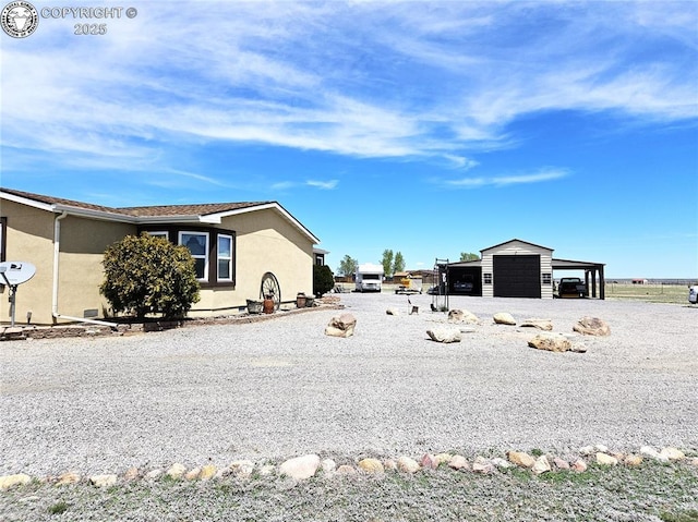 view of side of property with stucco siding, an outbuilding, and a detached garage
