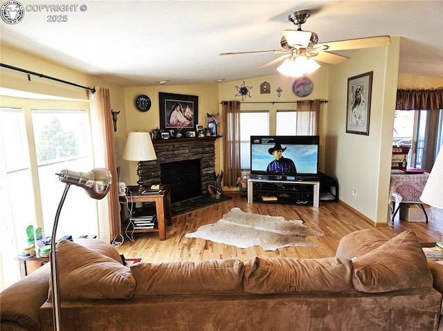 living area featuring wood finished floors, a ceiling fan, a fireplace, and baseboards