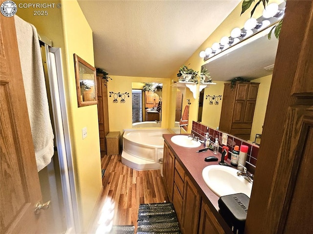 bathroom featuring a garden tub, wood finished floors, and double vanity