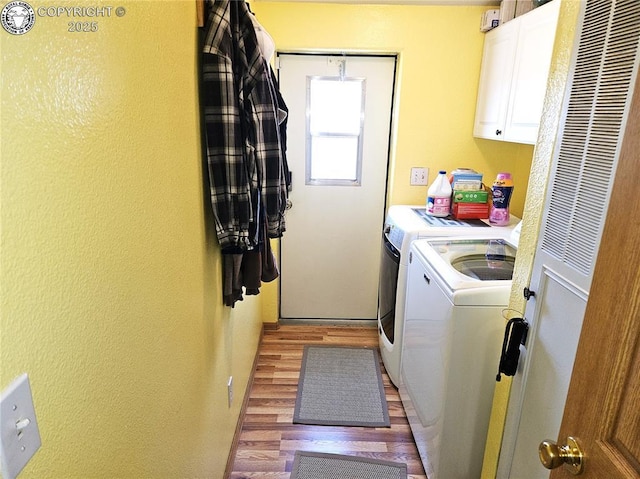 laundry area featuring washing machine and dryer, cabinet space, a heating unit, light wood-style floors, and a textured wall