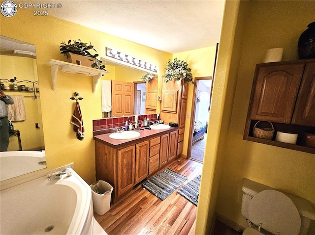 full bathroom with wood finished floors, double vanity, and a bath