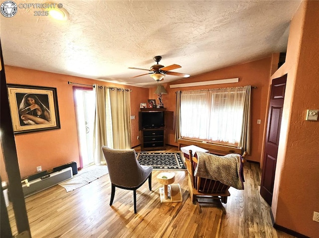 sitting room with healthy amount of natural light, wood finished floors, a ceiling fan, a textured ceiling, and vaulted ceiling