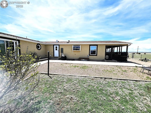 view of front of property featuring stucco siding, a patio, and fence