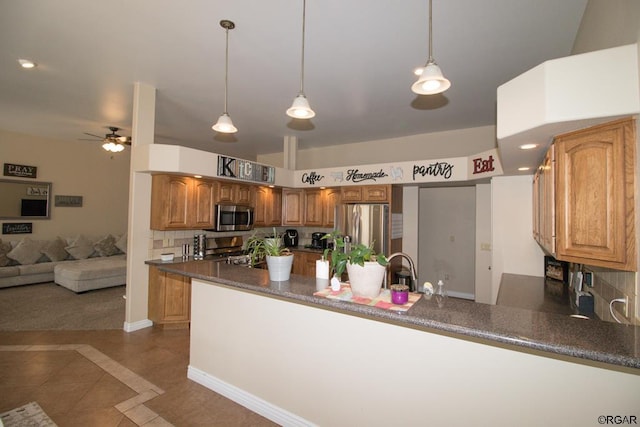 kitchen featuring decorative light fixtures, appliances with stainless steel finishes, kitchen peninsula, dark tile patterned floors, and decorative backsplash