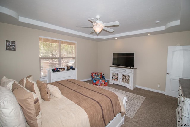 carpeted bedroom with a raised ceiling and ceiling fan