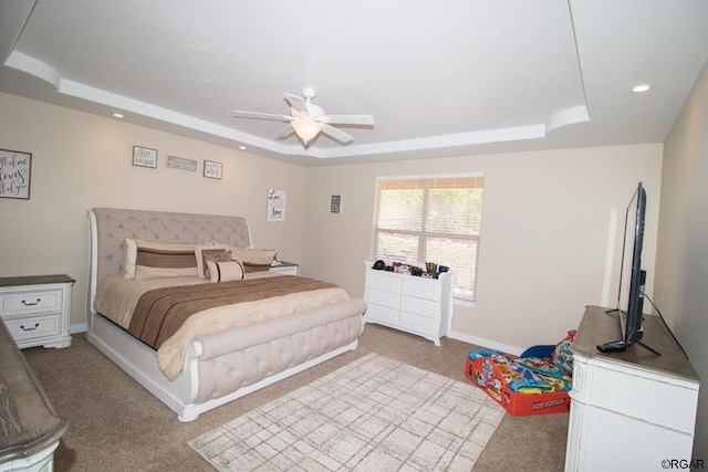 carpeted bedroom with ceiling fan and a raised ceiling