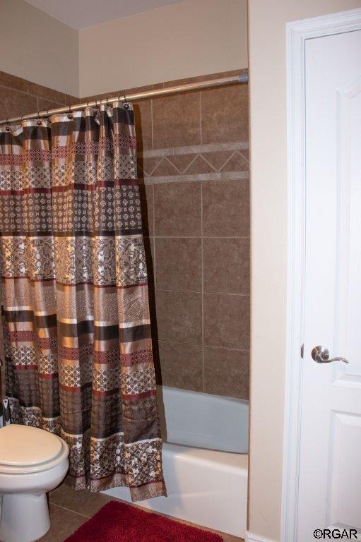 bathroom featuring tile patterned flooring, shower / tub combo, and toilet