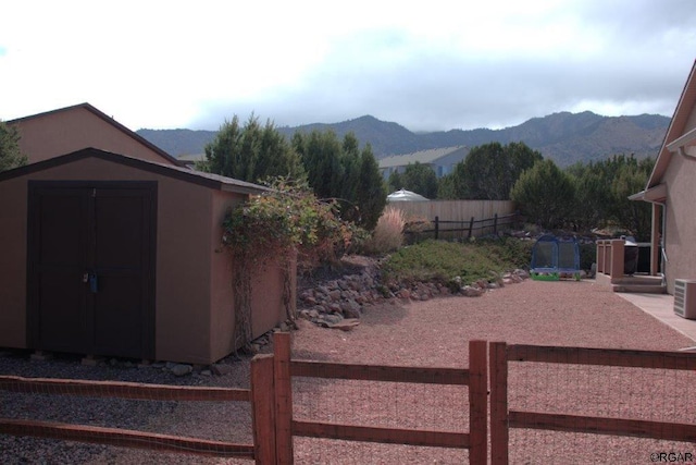 view of yard with a trampoline, a mountain view, and a storage unit