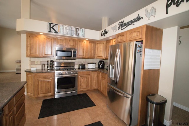 kitchen with tasteful backsplash, light tile patterned flooring, dark stone countertops, and appliances with stainless steel finishes