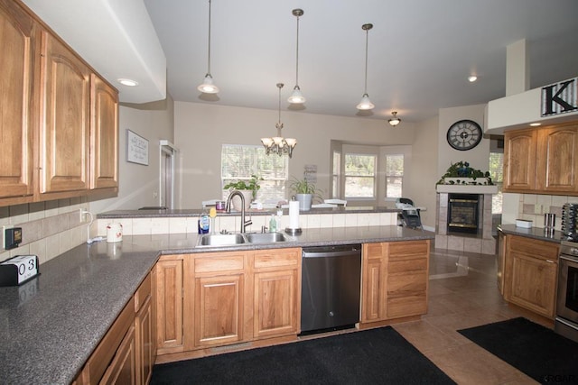 kitchen featuring a tile fireplace, tasteful backsplash, sink, dishwashing machine, and hanging light fixtures